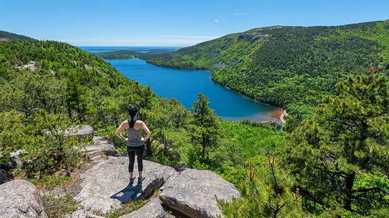 Reaching the edge of a cliff a top North Bubble Hiking Trail in Maine.
