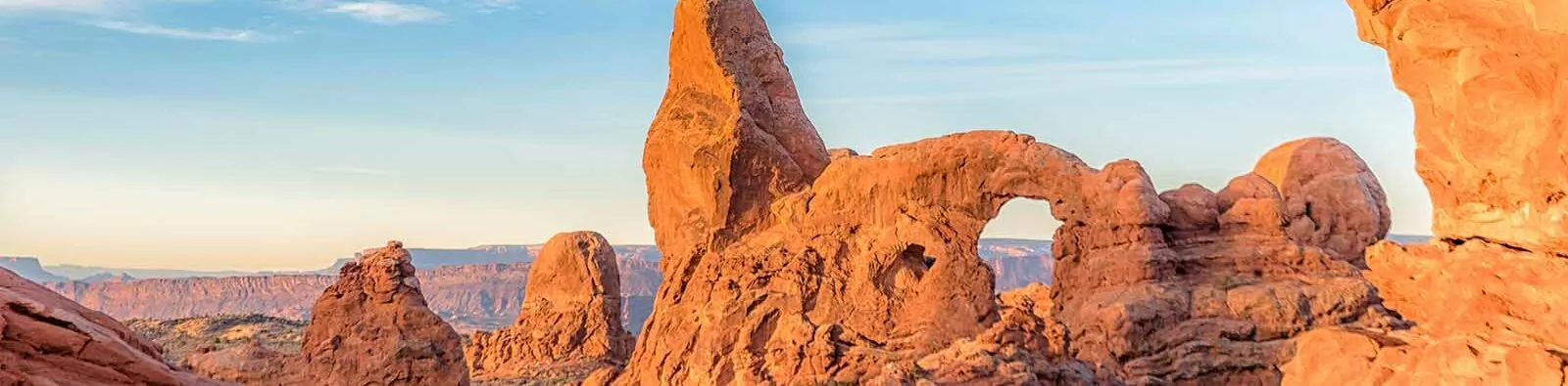 A woman walks through North Window Arch with Turret Arch in the background
