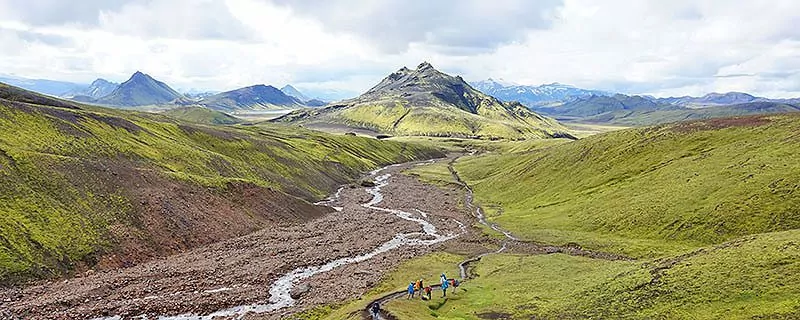 Group of hikers on trail by stream