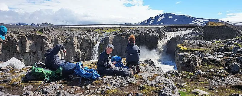 Hikers sitting on rocks, looking at waterfall