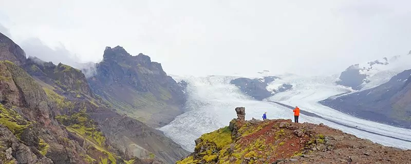 Hikers on grass cliff overlooking water